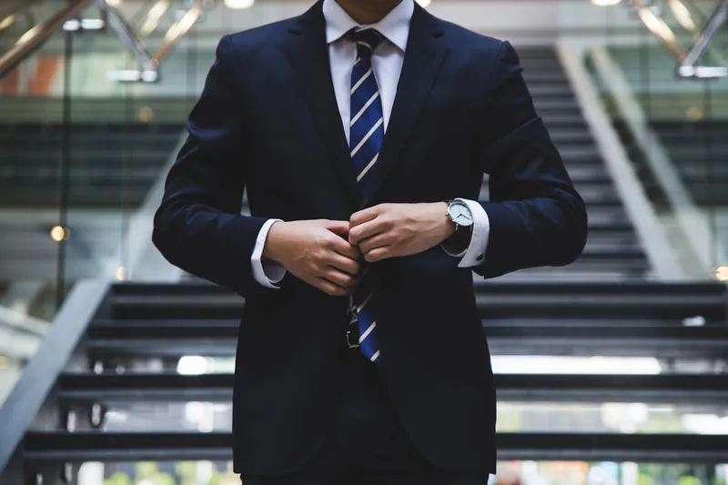 Costum bleumarin închis clasic cu doi nasturi, cravată în dungi, ceas la mână